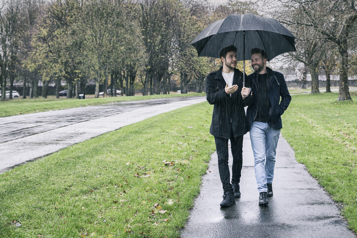 Gay couple sharing an umbrella