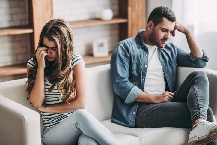 Upset couple at home. Handsome man and beautiful young woman are having quarrel.