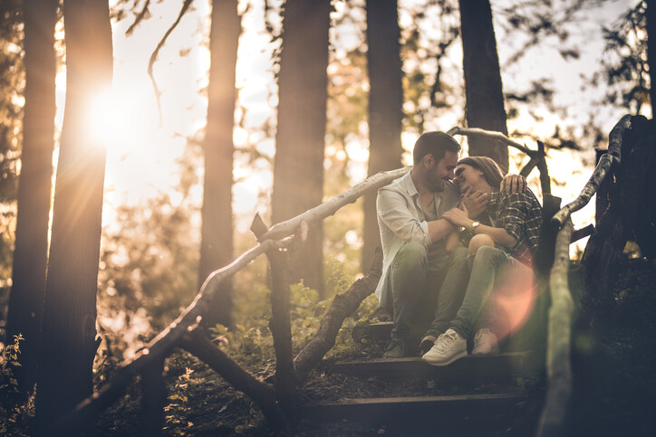 Young loving couple sitting on staircase in nature and enjoying in their love at sunset.