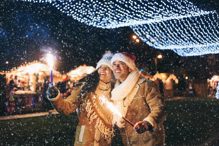 Young couple having fun with sparkling candles at night