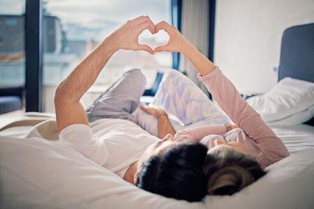 Couple is lying on the bed and making heart with their hands, unconscious bias