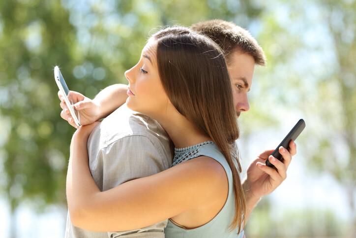 Couple hugging and texting everyone on their smart phones
