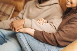 Two people enjoy a tender moment together on a comfortable couch in a rustic living room, surrounded by warm colours and relaxing ambiance in the early evening.