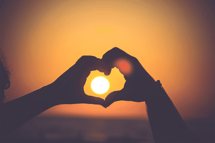 hands making heart around sun