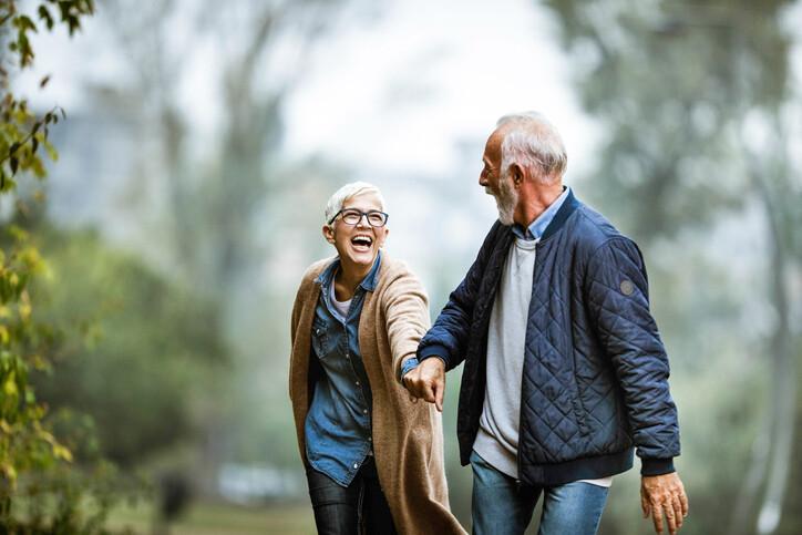 Cheerful senior couple having fun in the park. Focus is on woman. Copy space., dating
