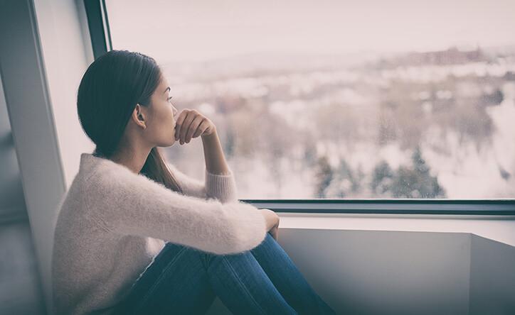 Woman looking out of window with relationship anxiety