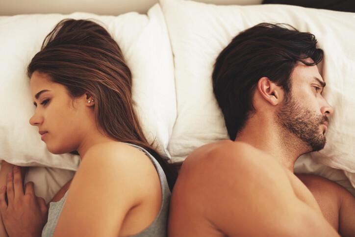 Shot of a young couple lying in bed and ignoring each other