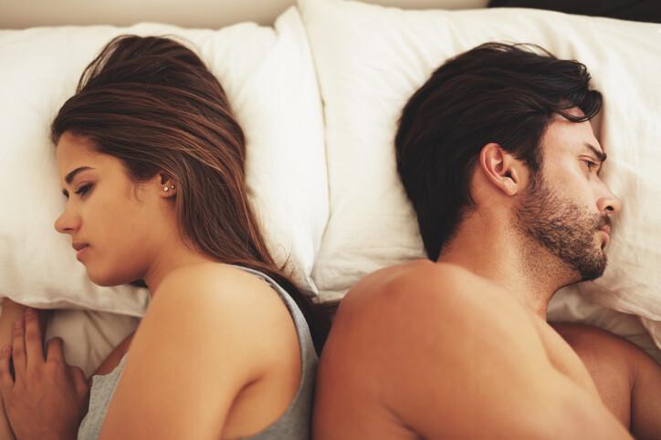 Shot of a young couple lying in bed and ignoring each other