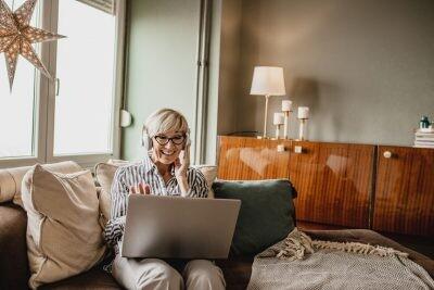 Mature woman is in her modern apartment using a laptop to create her online dating profile