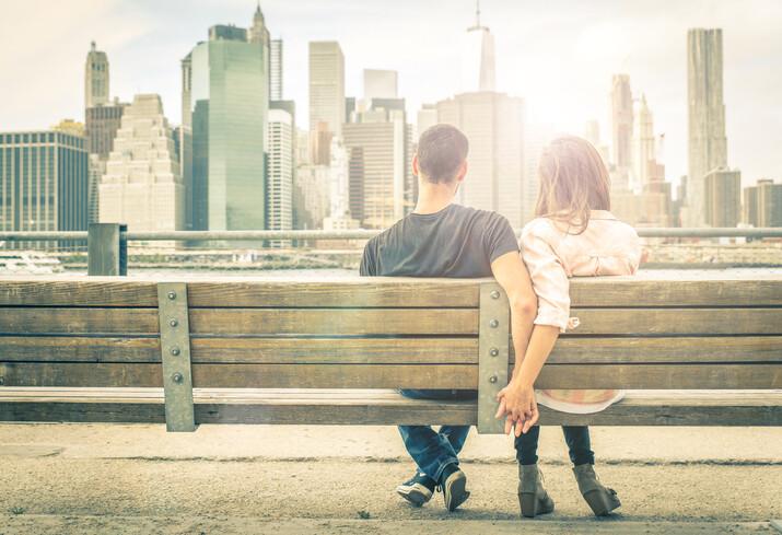 couple relaxing on New york bench in front of the skyline at sunset time. concept about love,relationship, and travel