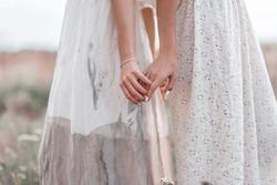 Two women in white dresses holding hands